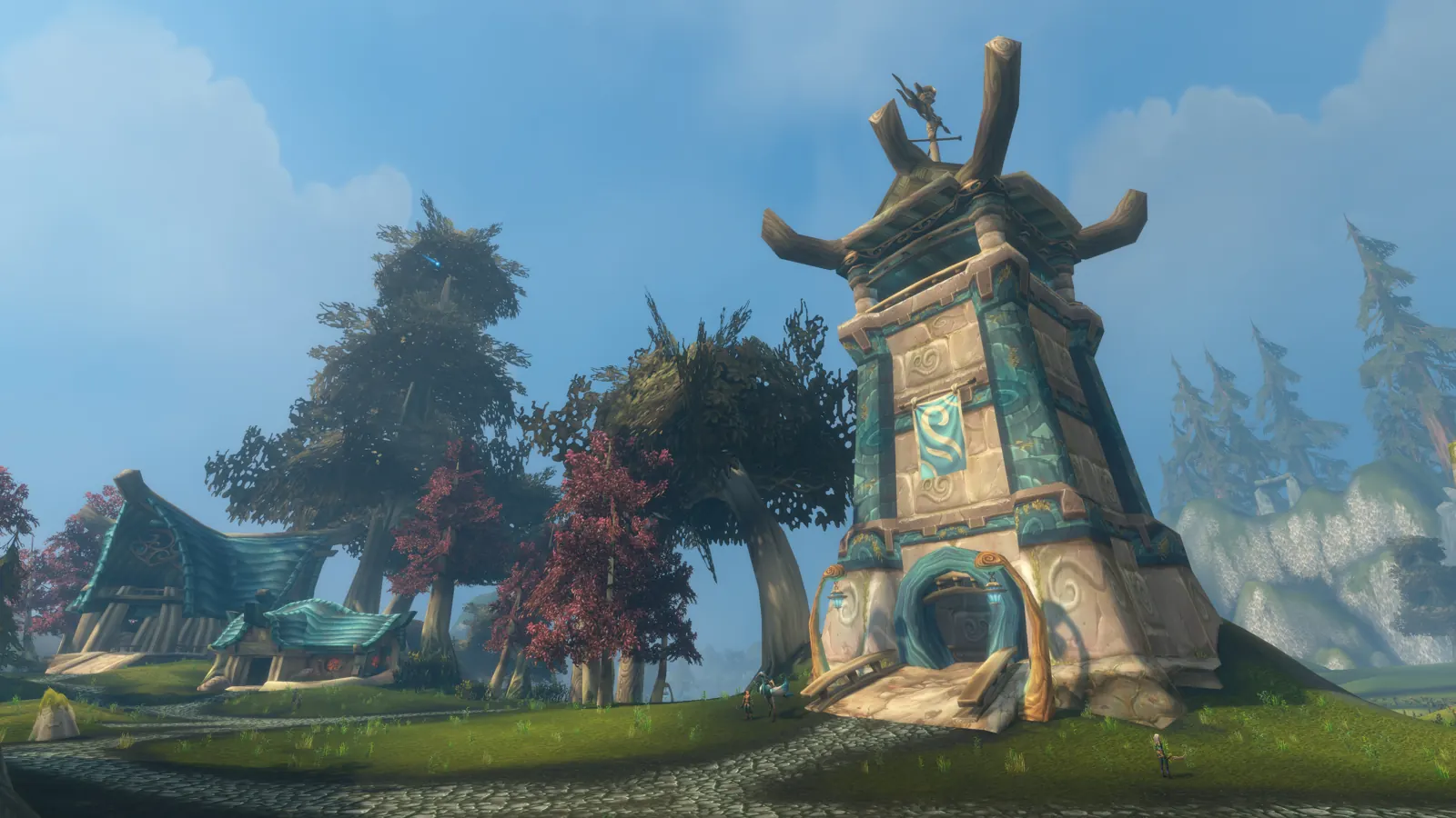A carved stone shrine tower with a blue emblem, next to blue-roofed houses